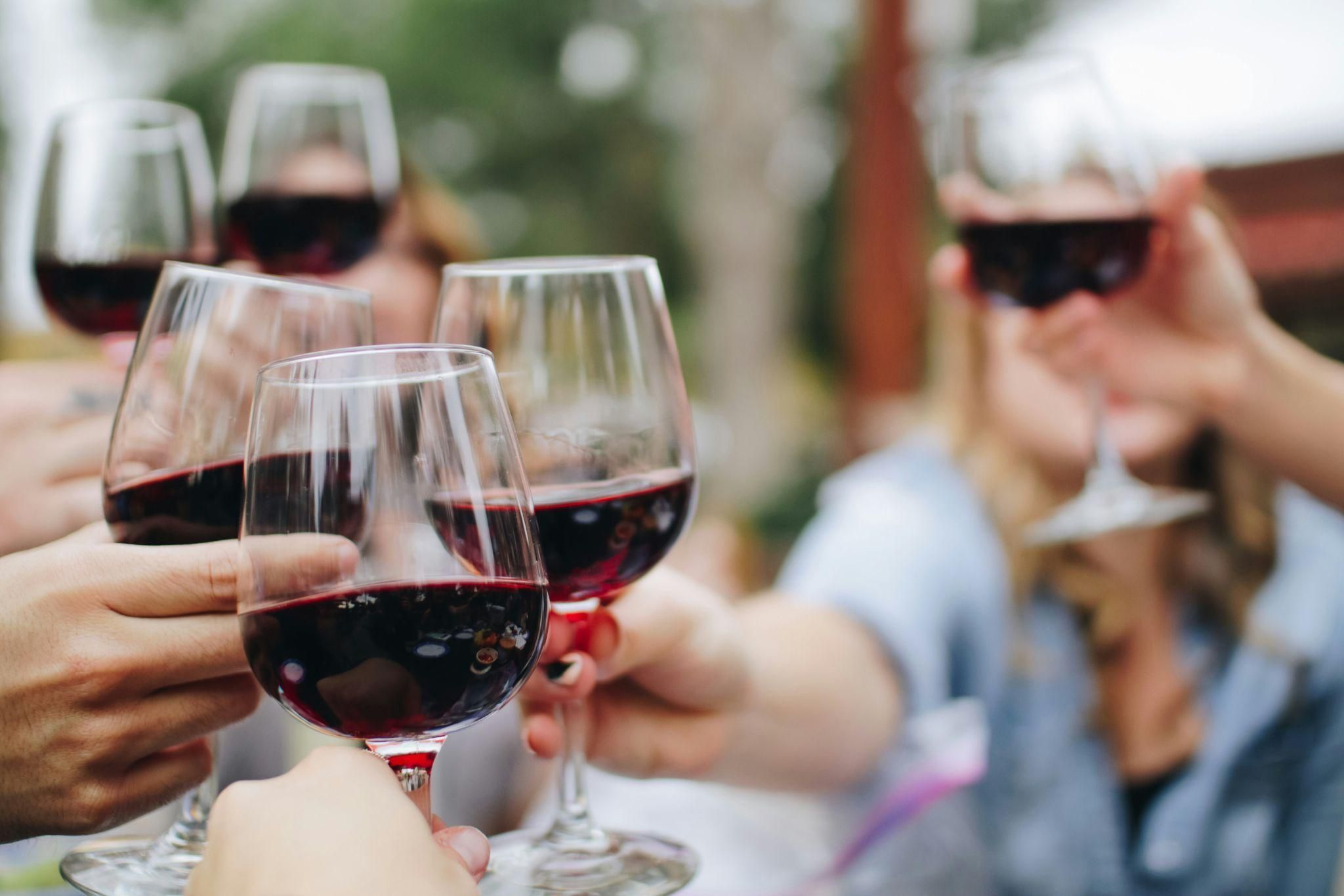 A glass of wine on an edge with vineyards and a body of water in the background